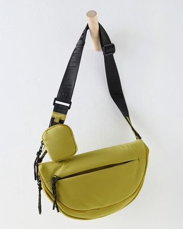 hanging green crescent shaped sling bag with black adjustable strap and small pouch attached