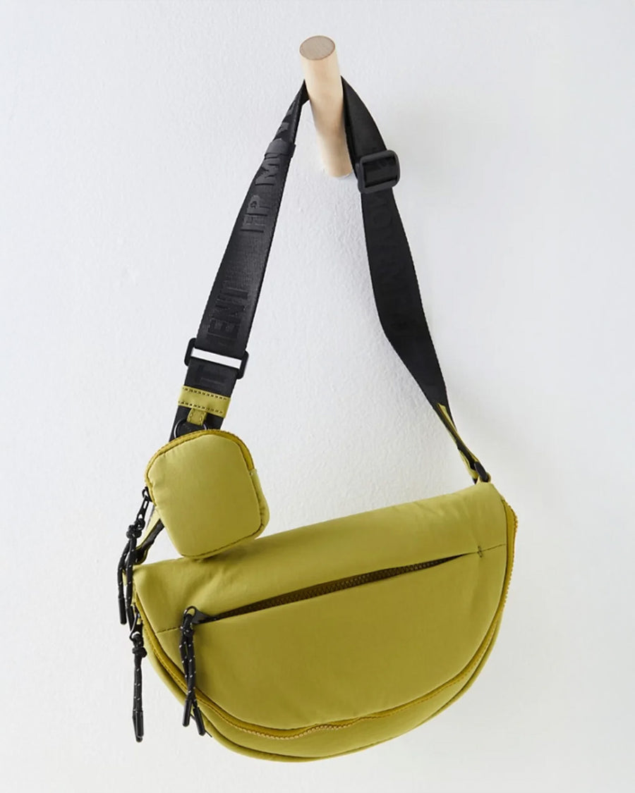 hanging green crescent shaped sling bag with black adjustable strap and small pouch attached