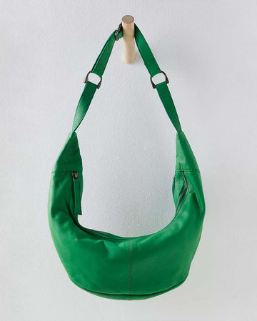 clover green leather bag with small crescent shape, interior pocket and zip closure hanging on a wooden peg