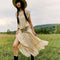 model wearing cream shapeless maxi dress with intricate tank top sleeves, tiered skirt with various lace detail 