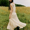 back view of model wearing cream shapeless maxi dress with intricate tank top sleeves, tiered skirt with various lace detail 