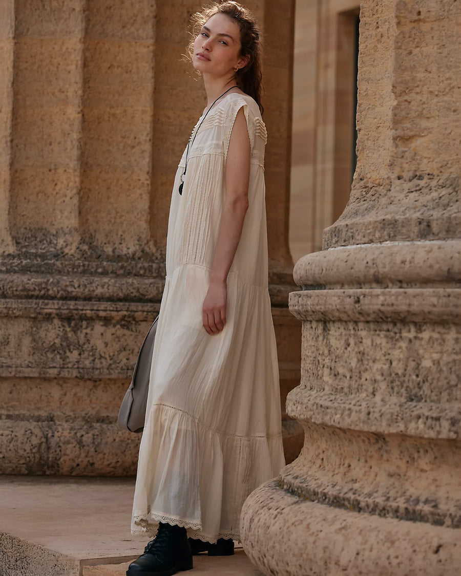 model wearing cream shapeless maxi dress with intricate tank top sleeves, tiered skirt with various lace detail 