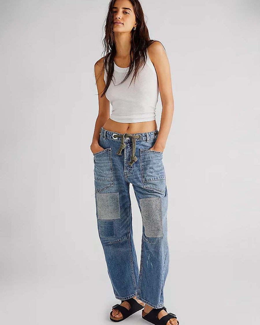 model wearing low-rise barrel jeans with slight distressing and denim colored patches