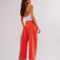 back view of model wearing bright red pants with relaxed fit and waist detail