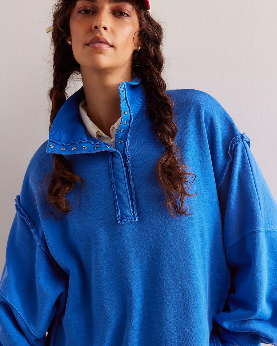 up close of model wearing cobalt blue oversized sweatshirt with snap henley front and slits on the cuffs