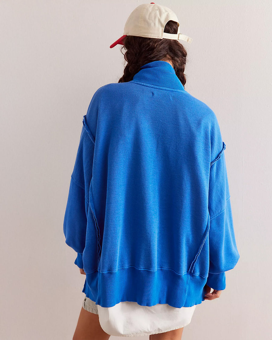 back view of model wearing cobalt blue oversized sweatshirt with snap henley front and slits on the cuffs