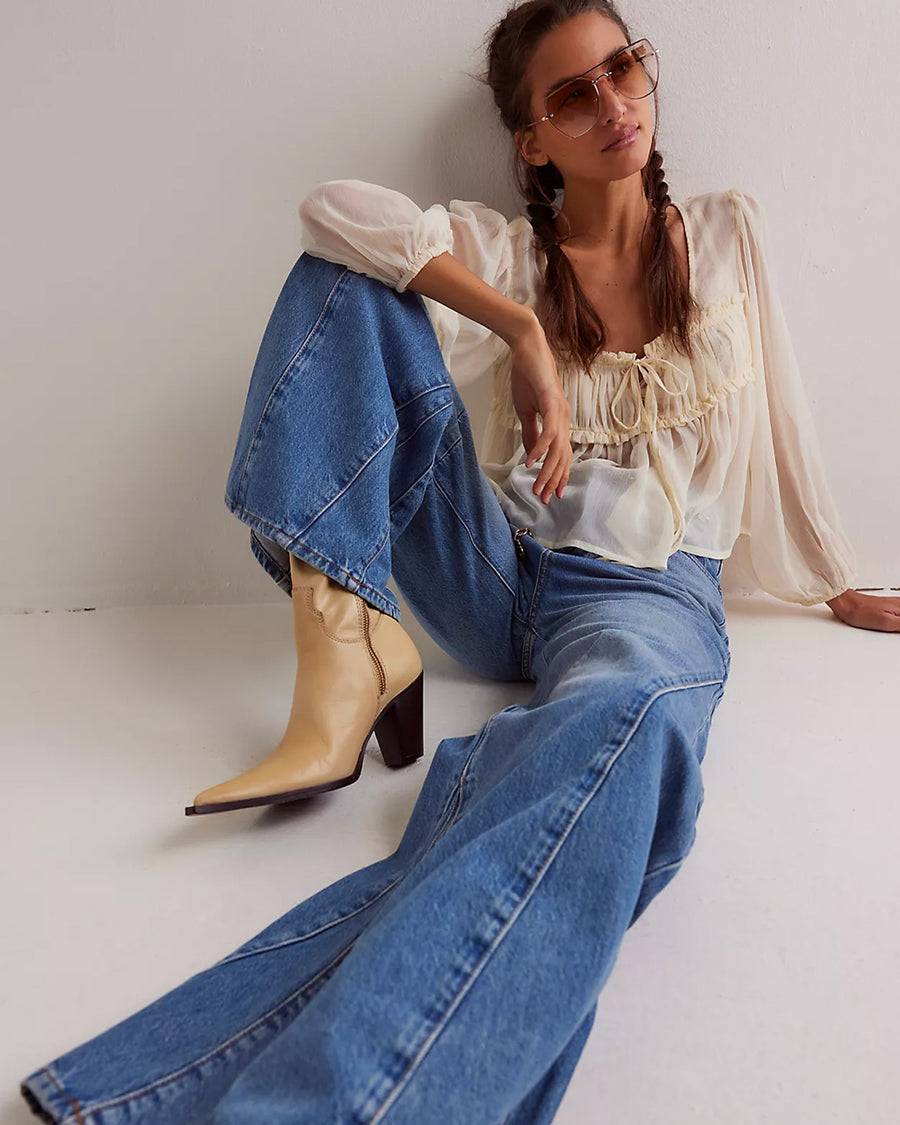 up close of model wearing medium washed denim with flared buttons