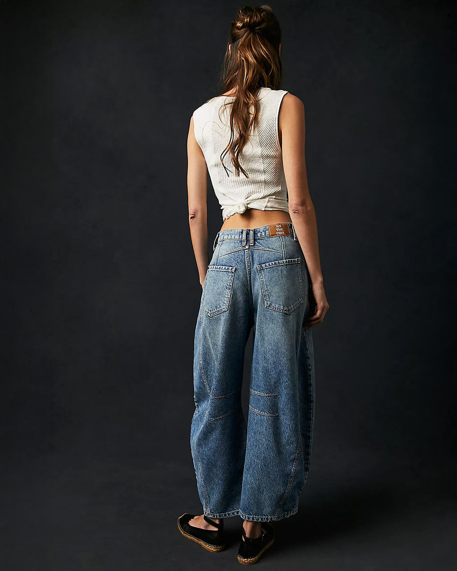 back view of model wearing light denim wash barrel jeans with dart detail on the interior legs