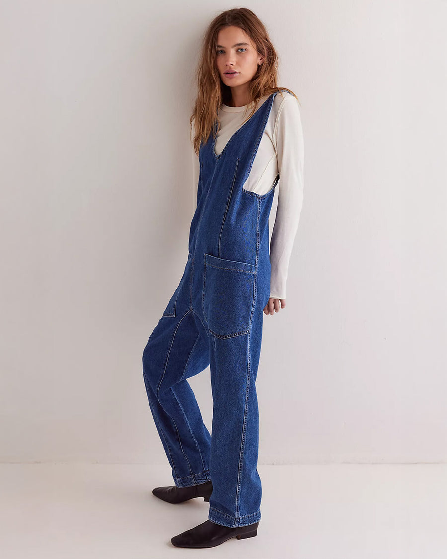 model wearing dark wash relaxed fit jumpsuit with front seaming and front patch pockets