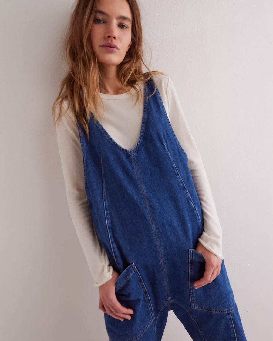 model wearing dark wash relaxed fit jumpsuit with front seaming and front patch pockets