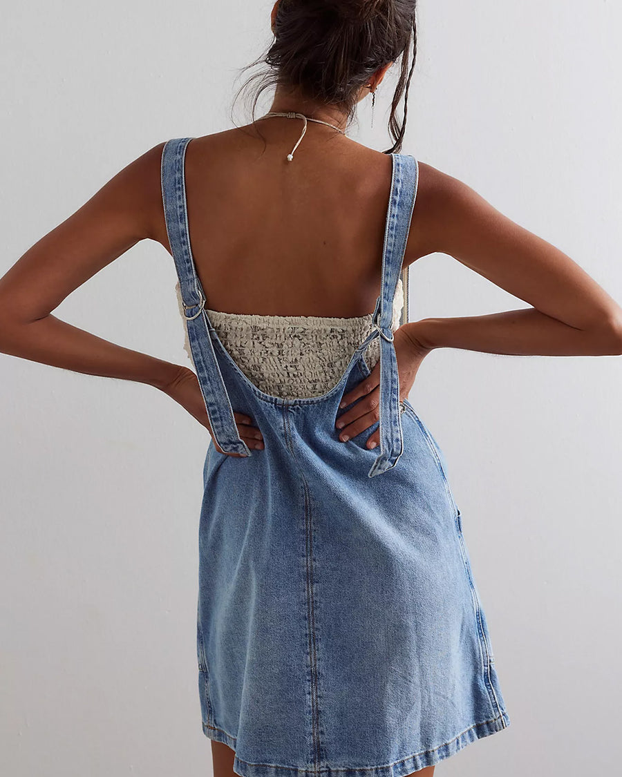 back view of model wearing light denim mini skirtall with front patch pockets