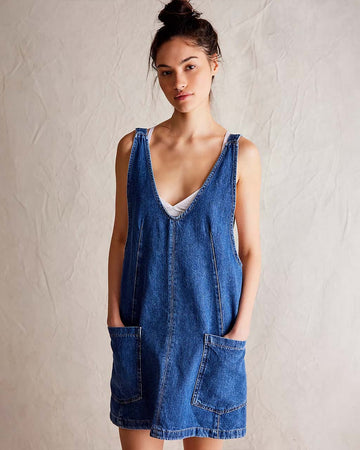 model wearing denim mini jumper dress with patch pockets and adjustable strap