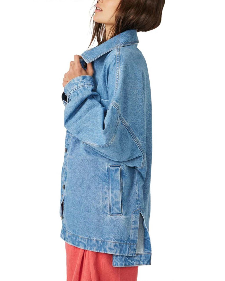 sideview of model wearing light denim oversized jacket with front patch pockets and button front