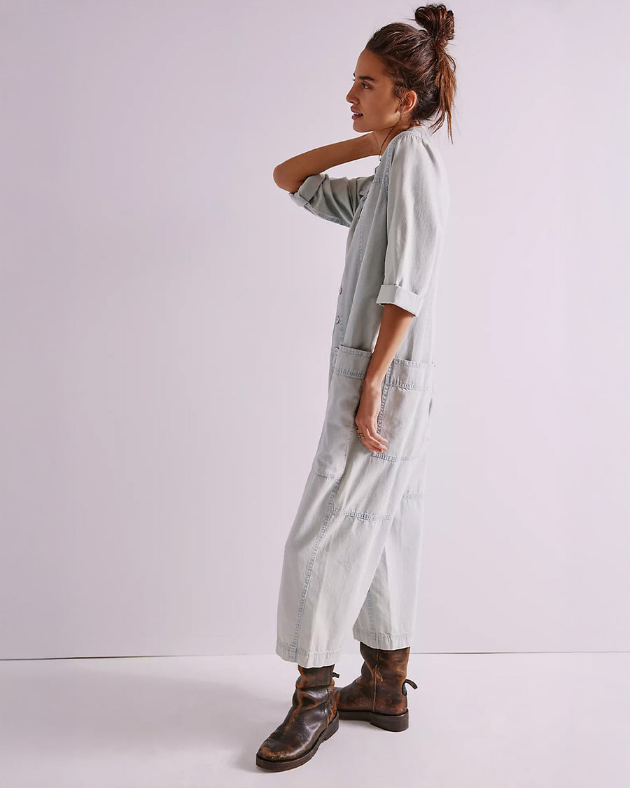 side view of model wearing light wash shapeless jumpsuit with button front and large front patch pockets