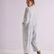 back view of model wearing light wash shapeless jumpsuit with button front and large front patch pockets