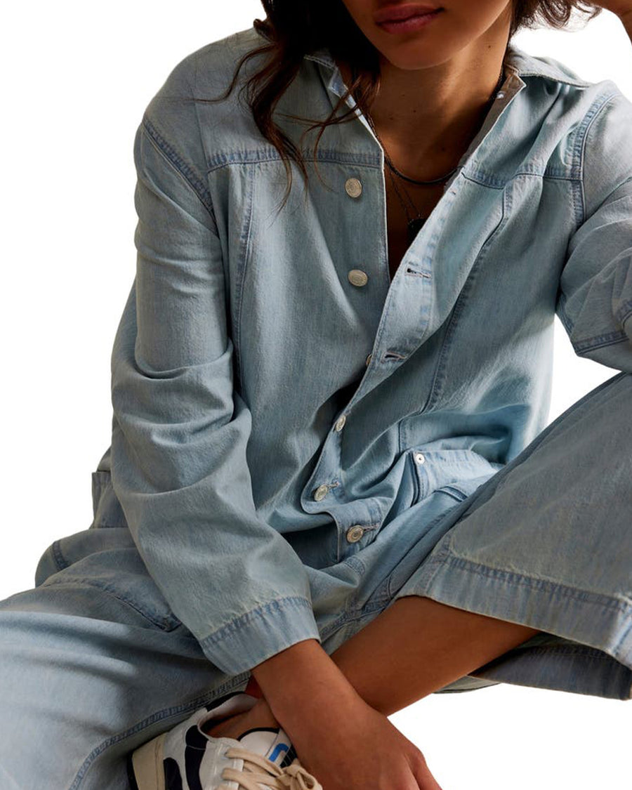 up close of model wearing light wash shapeless jumpsuit with button front and large front patch pockets