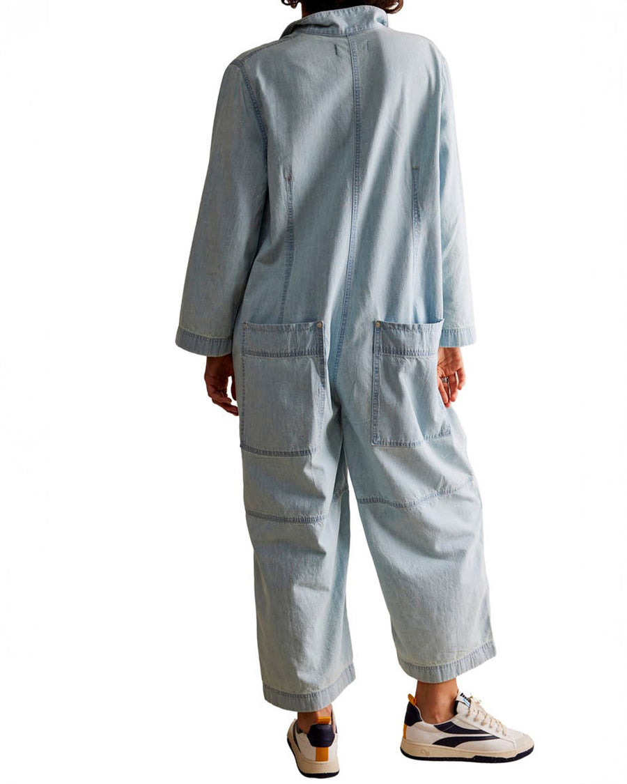 back view of model wearing light wash shapeless jumpsuit with button front and large front patch pockets