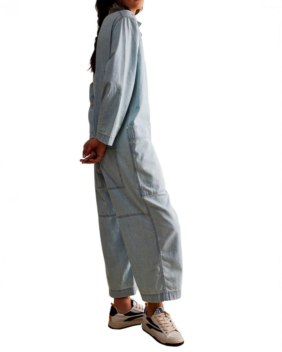 side view of model wearing light wash shapeless jumpsuit with button front and large front patch pockets