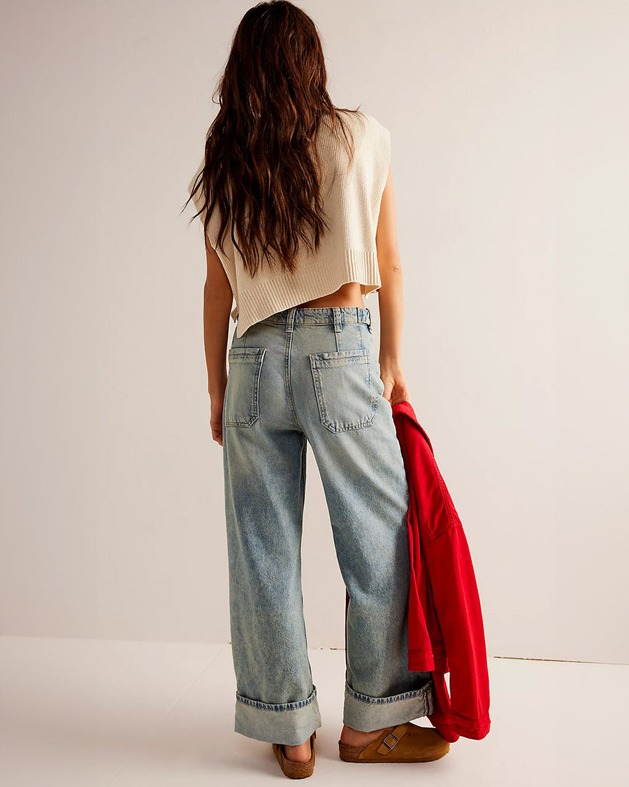 back view of side view of model wearing worn wash denim jeans with front sailor pockets and wide legs