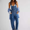 model wearing medium blue overalls with front pockets, adjustable straps and side button openings