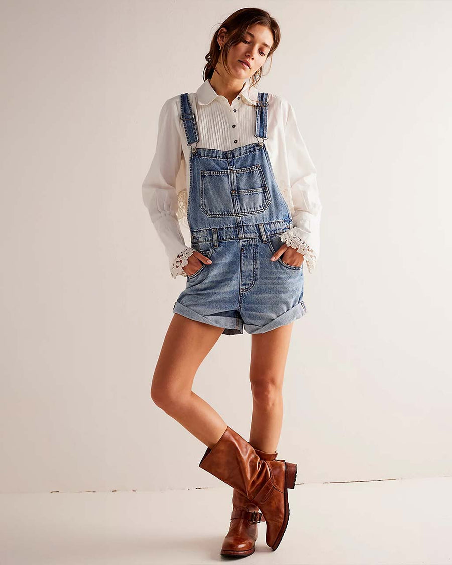 model wearing medium denim shortalls with front pockets, adjustable straps and front pouch pocket at the bust 