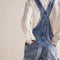 back view of model wearing medium denim shortalls with front pockets, adjustable straps and front pouch pocket at the bust 