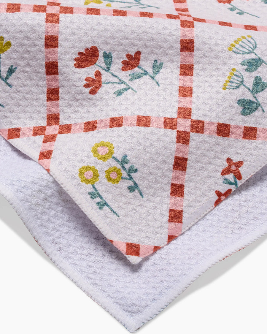 up close of light pink cottagecore tea towel with delicate floral and criss cross pattern