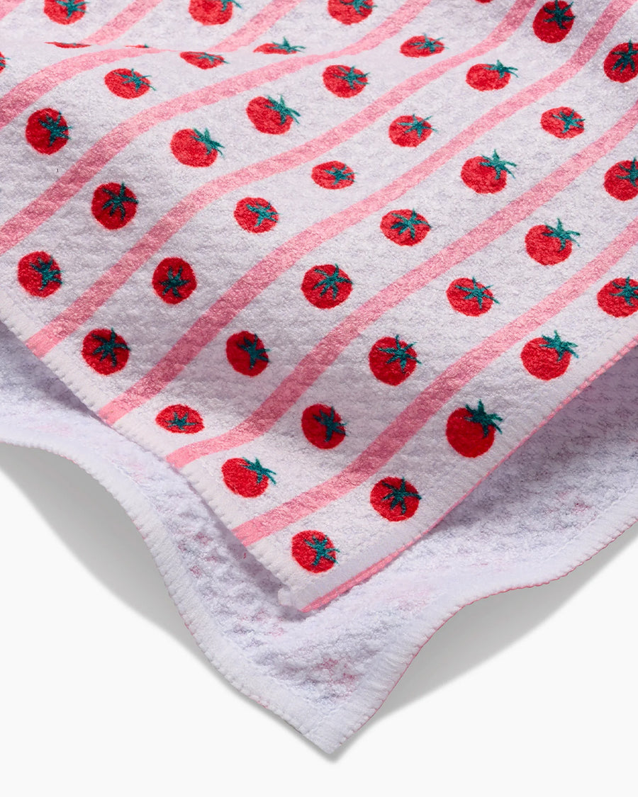 up close of white tea towel with tomato and stripe pattern