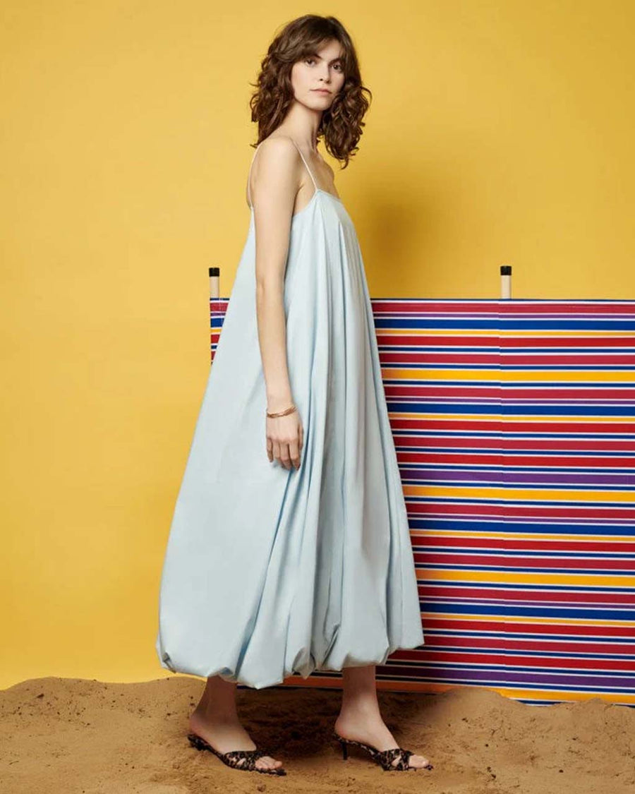 side view of model wearing light blue midi dress with spaghetti straps and bubble hem