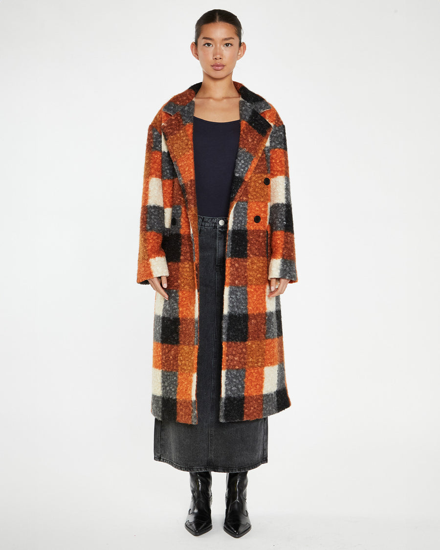 model wearing orange, black and grey checkered textured midi coat