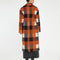 back view of model wearing orange, black and grey checkered textured midi coat