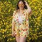 model wearing yellow trippy button down top with vibrant strawberry print and paired with matching shorts