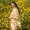 sideview of model wearing yellow trippy button down top with vibrant strawberry print and paired with matching shorts