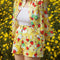 model wearing yellow trippy shorts with vibrant strawberry and flower print and paired with matching button down top