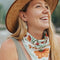 model wearing white square bandana with rust colored flowers and green leaf print around their neck