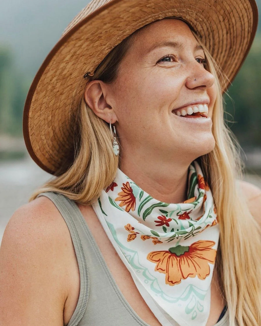 model wearing white square bandana with rust colored flowers and green leaf print around their neck