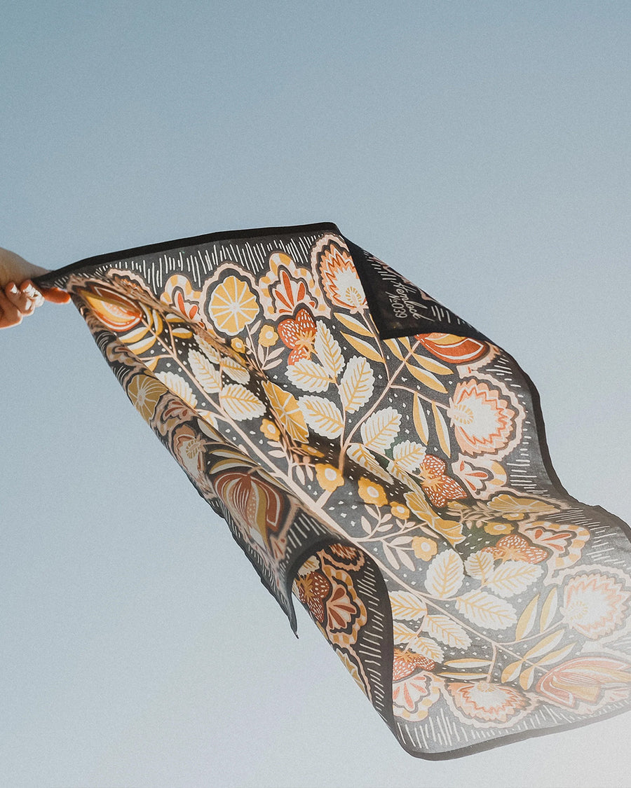 navy square bandana with yellow and mauve boho floral print blowing in the wind