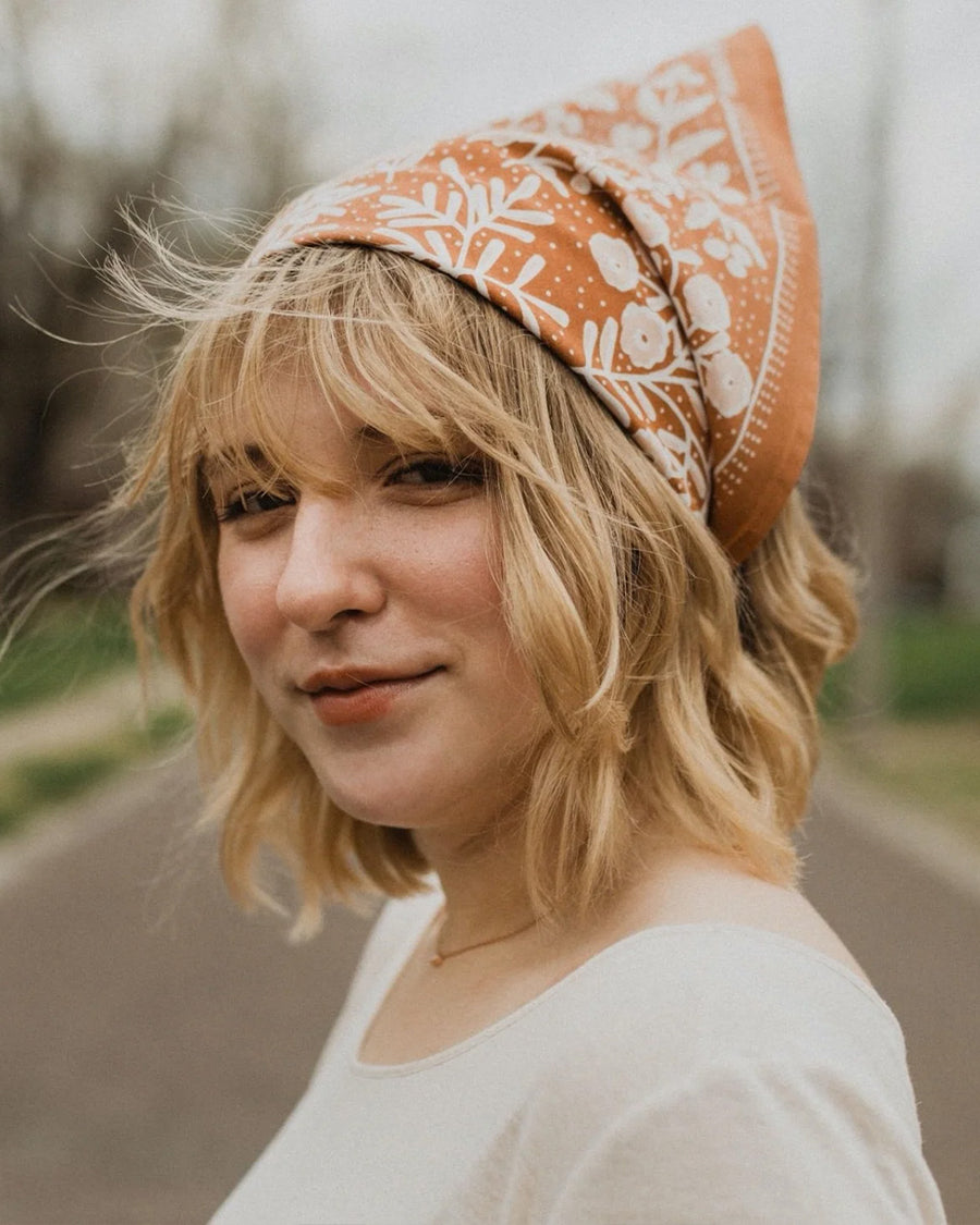 model wearing terracotta square bandana with light pink floral print