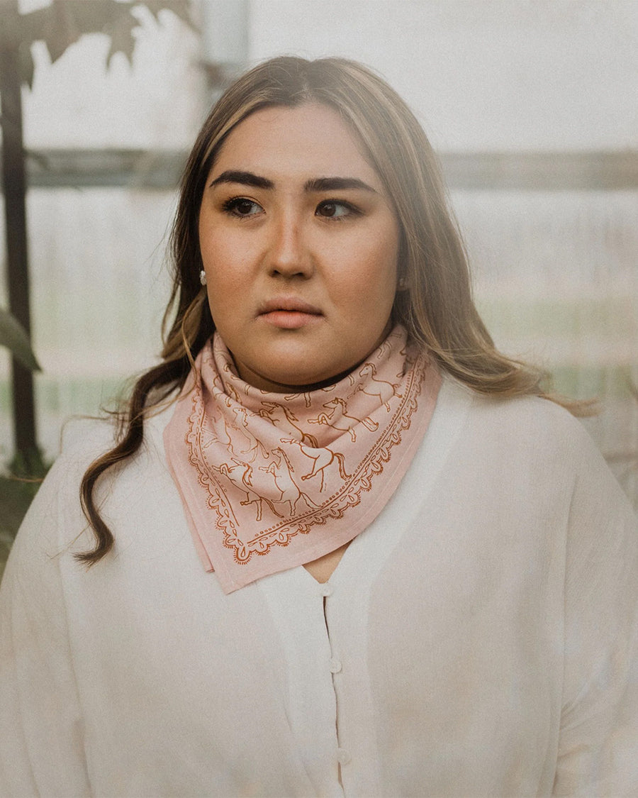 model wearing pink square bandana with galloping horse print