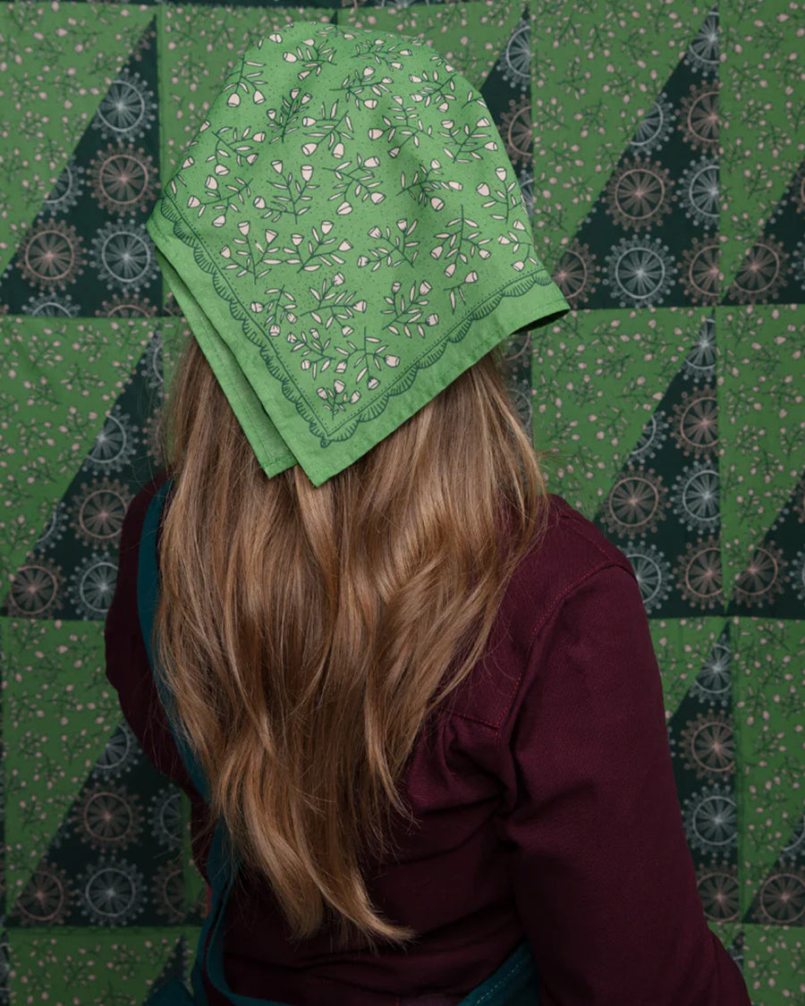 model wearing kelly green square bandana with dainty white floral print in their hair