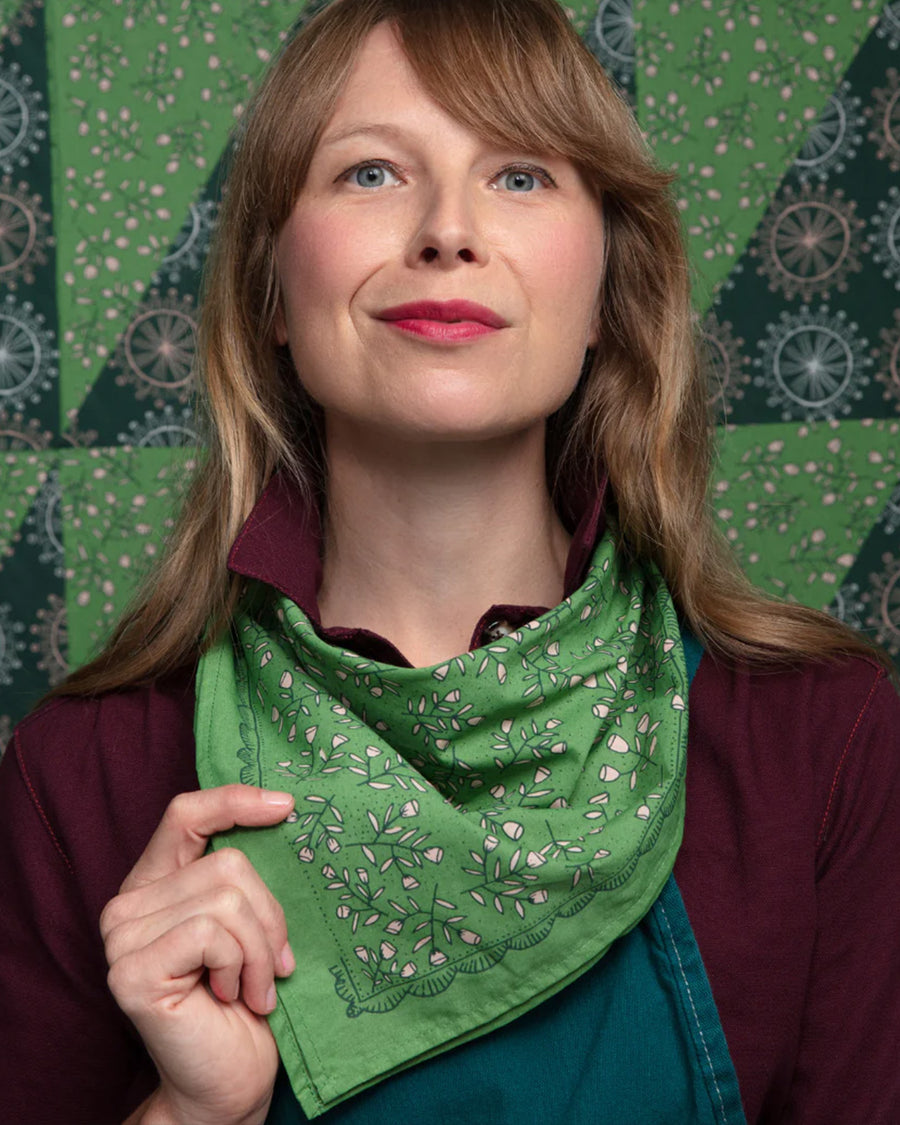 model wearing kelly green square bandana with dainty white floral print around their neck