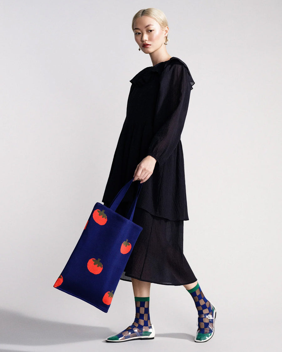 model carrying blue tote bag with all over tomato print