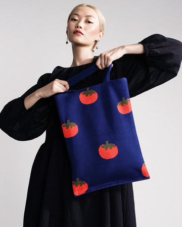 model holding blue tote bag with all over tomato print