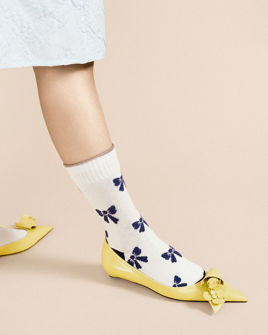 up close of model wearing white crew socks with blue bow print