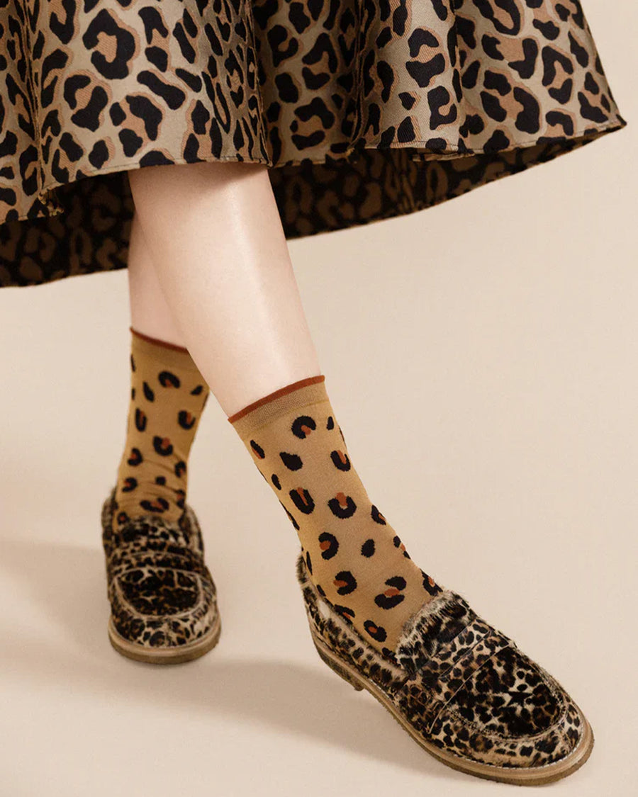 up close of model wearing light brown crew socks with black and brown leopard print