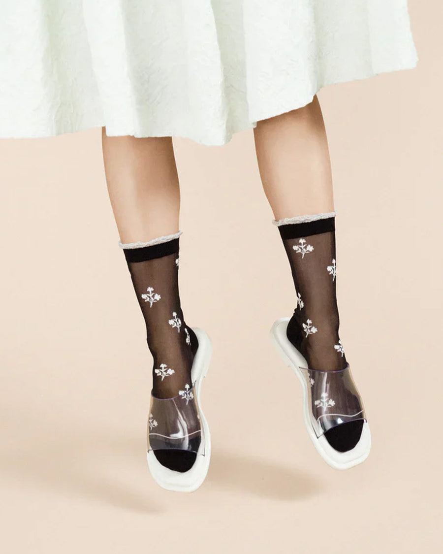 model wearing black sheer socks with white trim and dainty white flowers