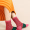 up close of model wearing pink and green space dye and speckled socks