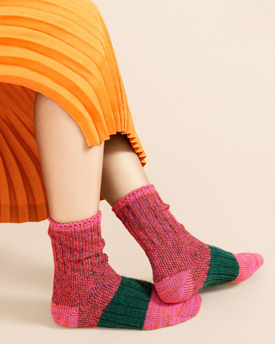 up close of model wearing pink and green space dye and speckled socks