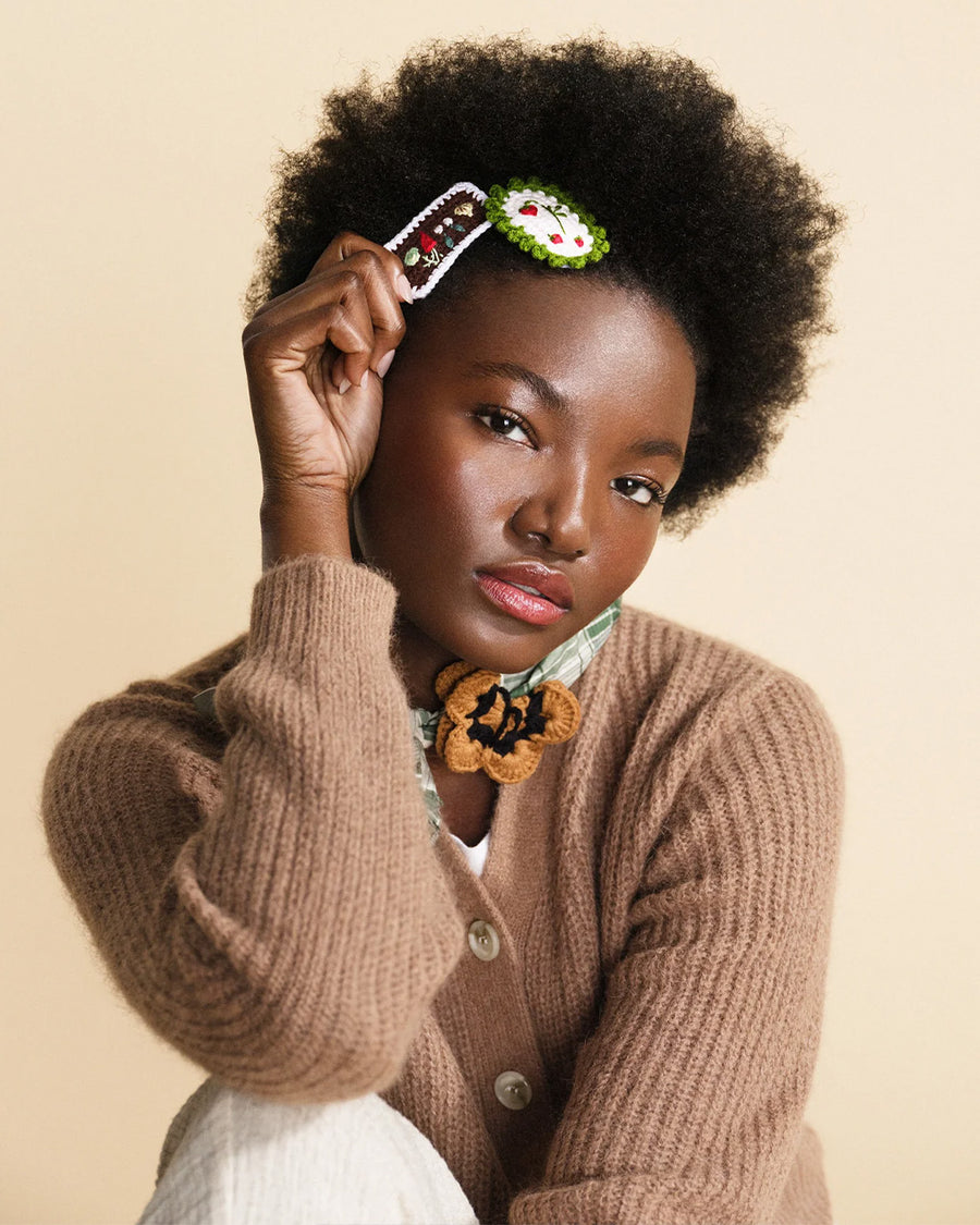 model wearing set of 2 hair clips: white strawberries with green border and brown veggies with white border