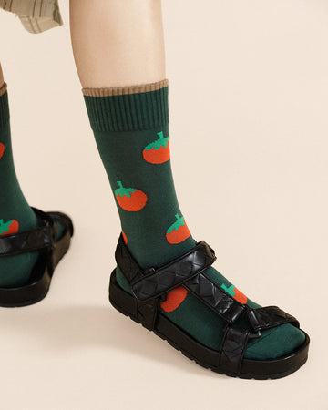 up close of model wearing green crew socks with all over tomato prints